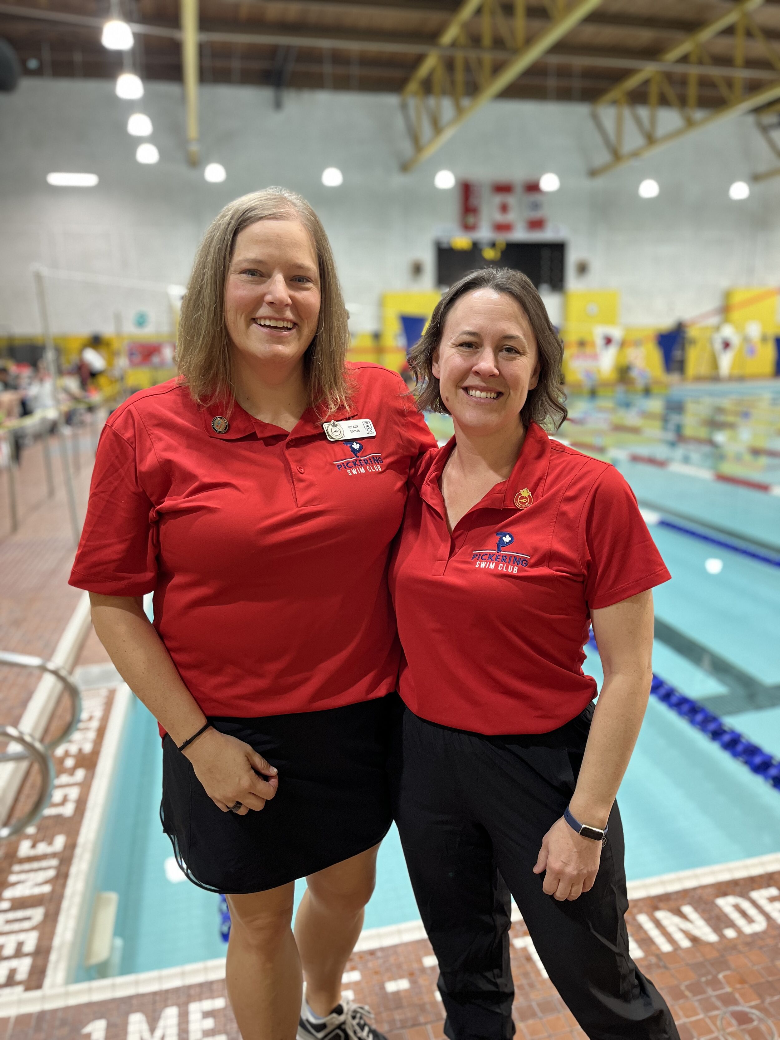 Two Pickering Swim Club officials smiling together beside the pool