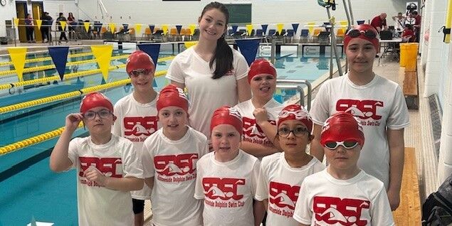 Group of young swimmers on deck wearing SDSC t-shirts and swim caps.
