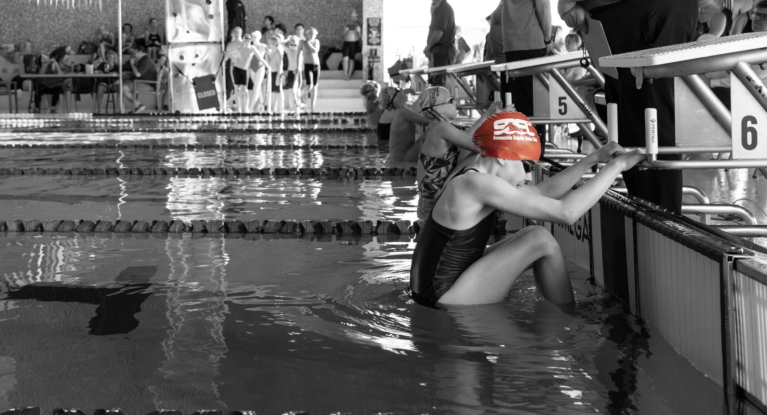 Group of young swimmers on deck wearing SDSC t-shirts and swim caps.